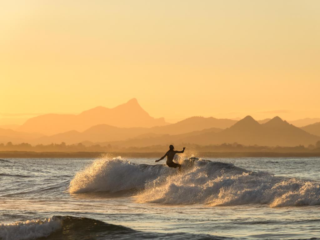 Surfer at sea, riding a wave during sunset