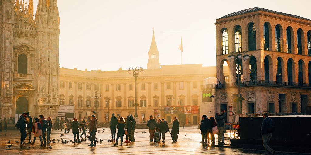 People walk in a city square in Milan, Italy, on a sunny day