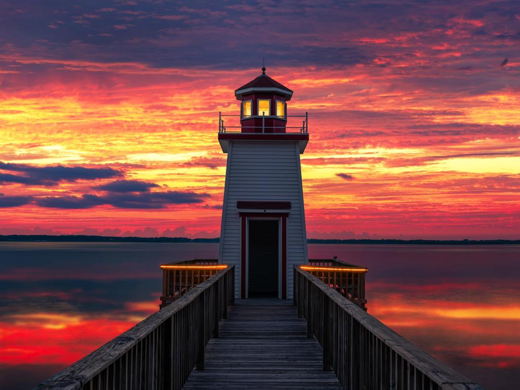 Beautiful lighthouse on the river with a fiery sunset in the background