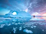 Red boat sailing past iceberg in Disko Bay in the summer - off the western coast of Greenland.