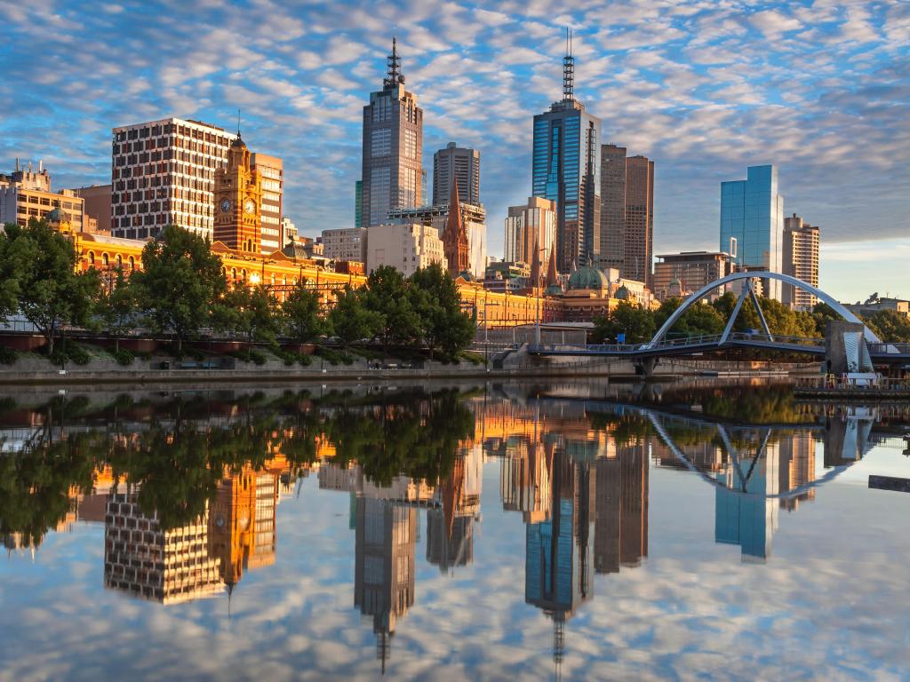 High rise buildings reflected in still water, blue sky with cotton wool clouds