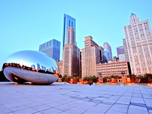 The famous Cloud Gate sculpture sits in front of the Chicago skyline at sunset