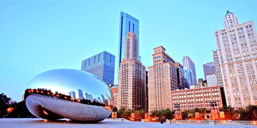 The famous Cloud Gate sculpture sits in front of the Chicago skyline at sunset