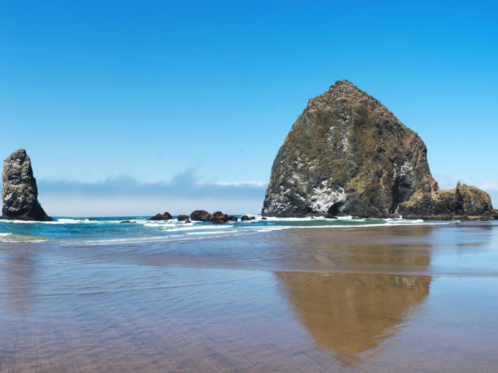 Haystack Rock, Cannon Beach, USA with the beach and sea in the foreground and the stunning rocks in the background taken on a clear sunny day.