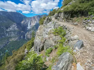 Rocky uneven pathway along Four Mile Trail, steep verges and mountain views in the distance
