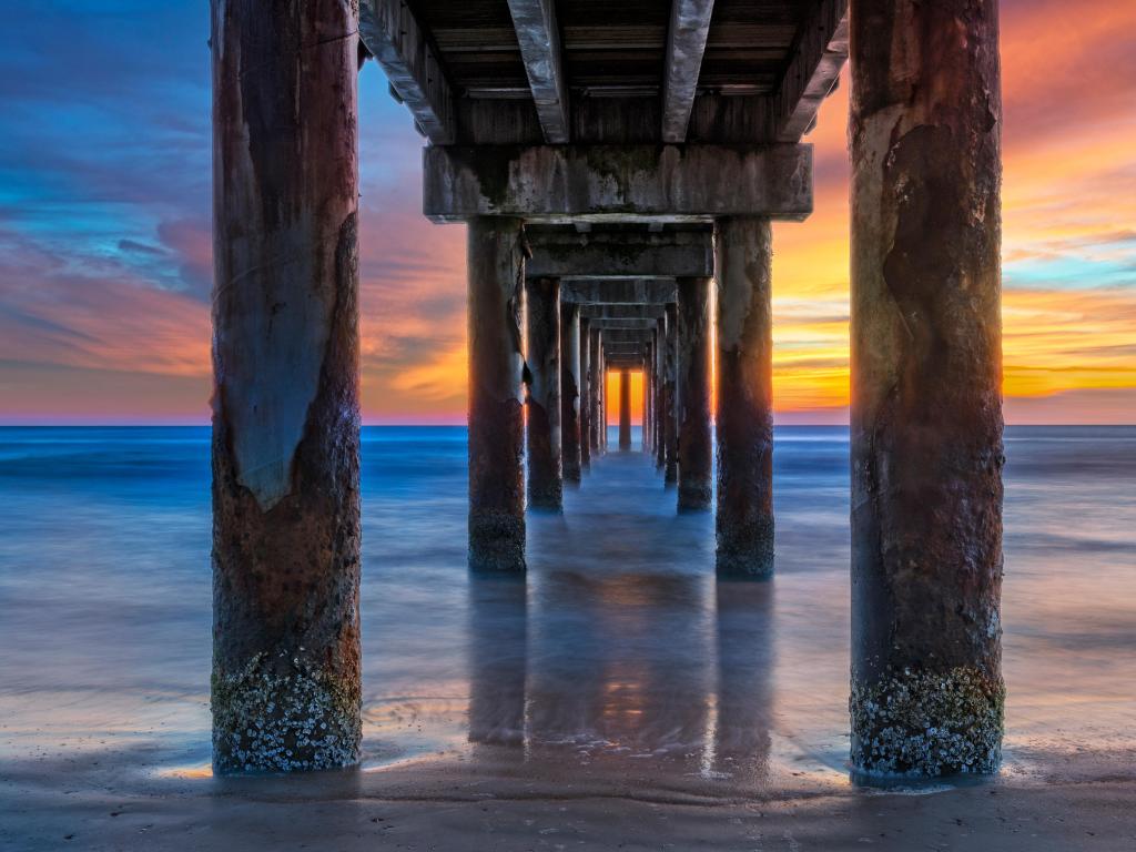 St. Augustine, Florida, USA with a sunrise under the St. Johns County Ocean Pier.