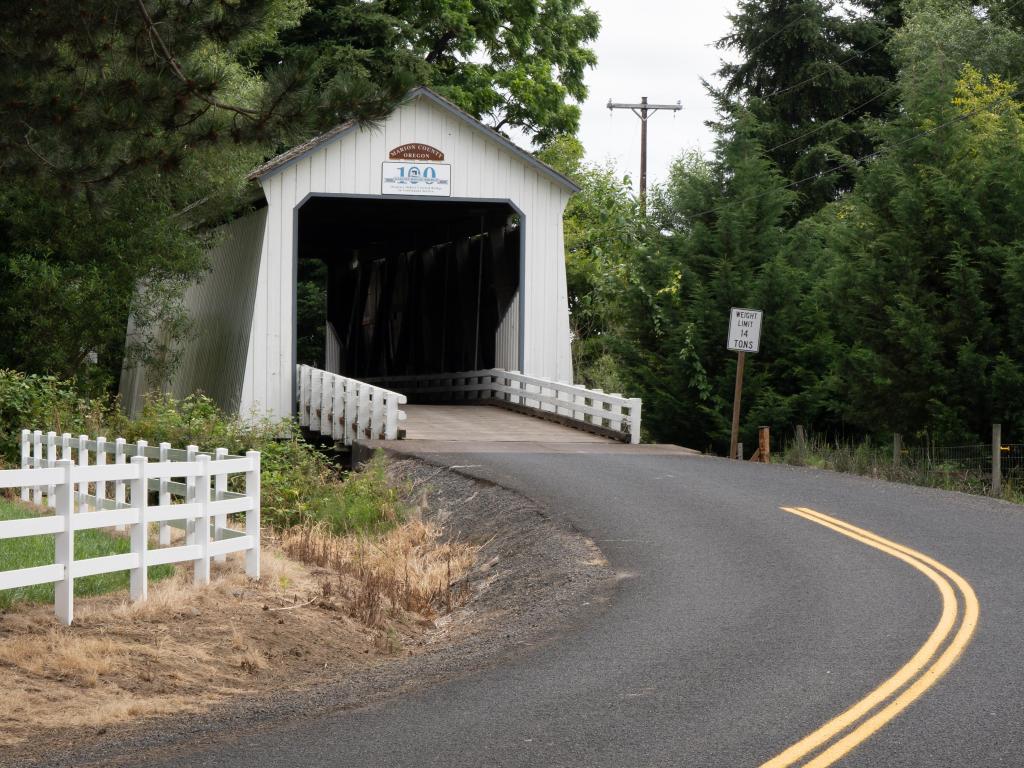 View from the winding road of Gallon House Covered Bridge near Silverton, Oregon. A historic white wooden structure