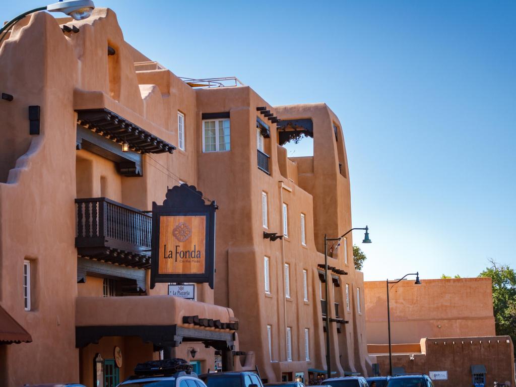 The brick-colored facade of the hotel, with a bright sky in the background