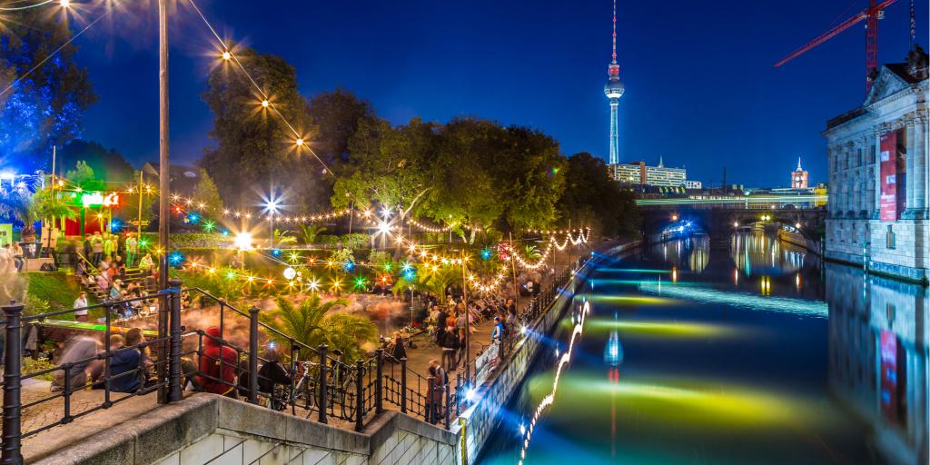 A bar lit up with fairy lights in Berlin at night, with the famous TV tower in the background 