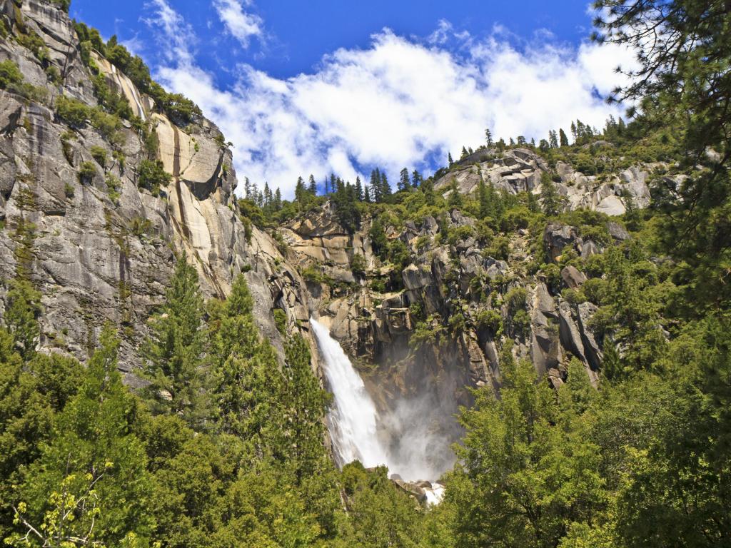 Wildcat Falls plunges between cliffs into forested Yosemite Valley
