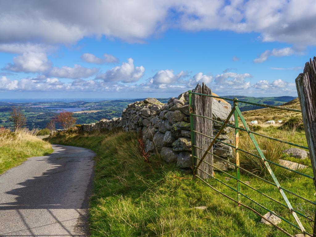 Colwyn Bay, Wales with a dry stone wall and painted gate foreground with view across the valley to the distant Gwynt y Môr (Sea wind) 576-megawatt offshore wind farm with 160 x 150m high turbines in Colwyn Bay Wales