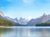 Maligne Lake in Jasper national park, Alberta, Canada taken on a sunny day with the lake in the foreground, trees and mountains in the distance.