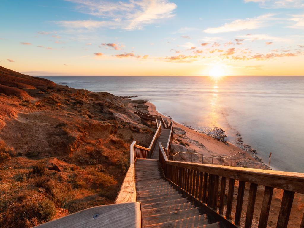 Sunset light over wooden steps down to white sand beach