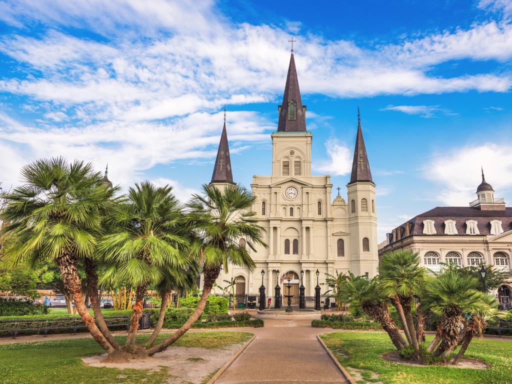 New Orleans, Louisiana, USA taken at Jackson Square and St. Louis Cathedral on a sunny day with palm trees in the foreground.