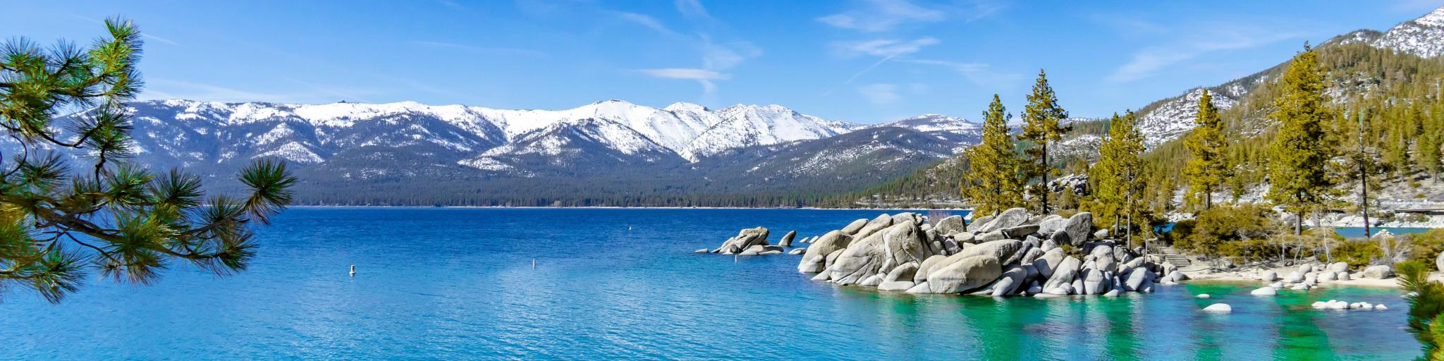 Clear Lake Tahoe on a clear day with snow-capped mountains in the background