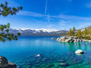 Clear Lake Tahoe on a clear day with snow-capped mountains in the background
