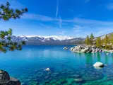 Clear Lake Tahoe on a clear day with snow-capped mountains in the background