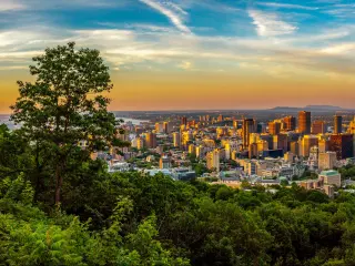 High rise downtown buildings with sliver of water behind and pink and gold sky