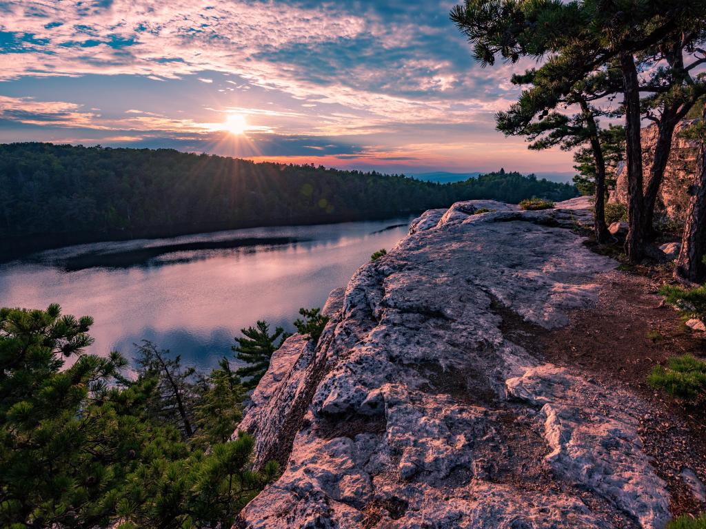 Minnewaska State Park, New York, USA with Lake Minnewaska and large rocks and trees in the foreground, taken at sunset.