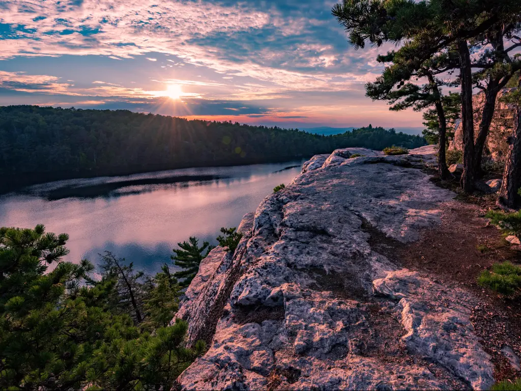 Minnewaska State Park, New York, USA with Lake Minnewaska and large rocks and trees in the foreground, taken at sunset.