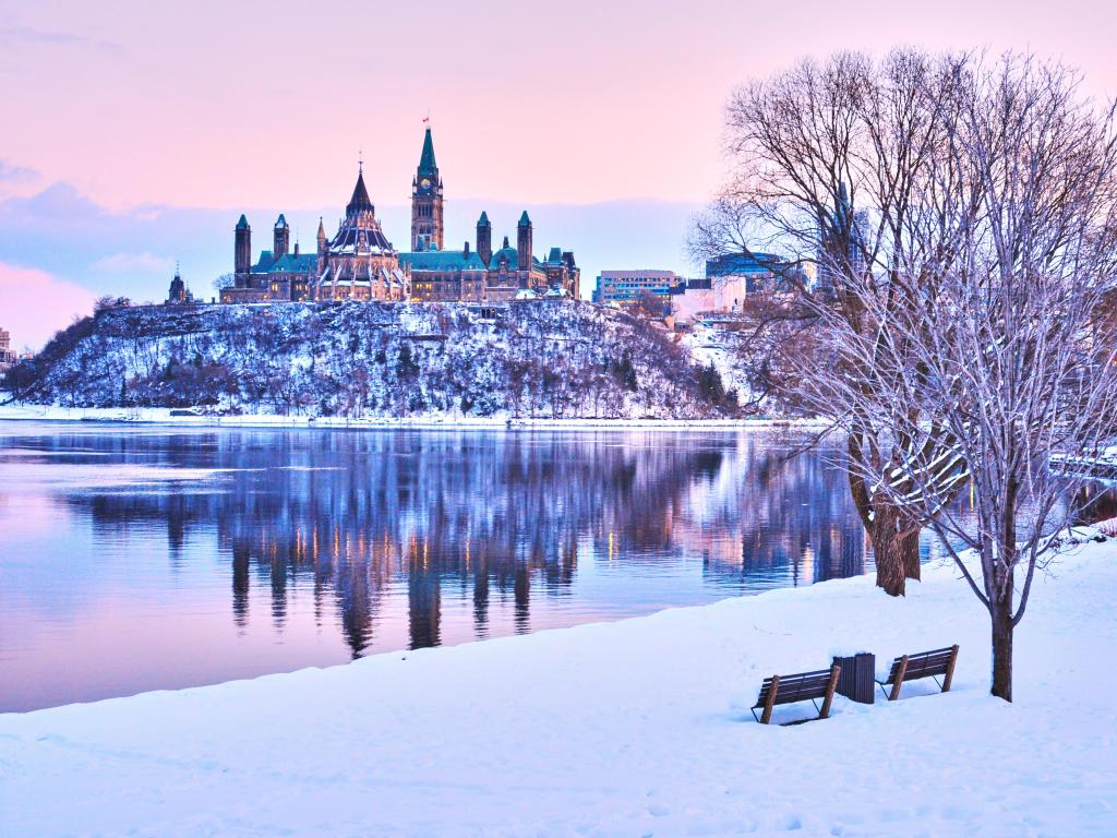 Ottawa in winter at dusk with a purple-hued sky and the water in the foreground