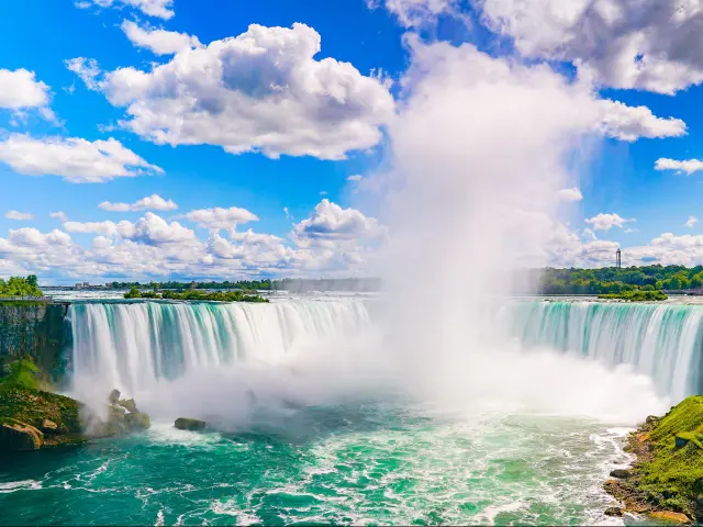 Niagara Falls, USA/Canada with the amazing falls in the center, taken on a sunny day with a few clouds and water spray rising in the air.