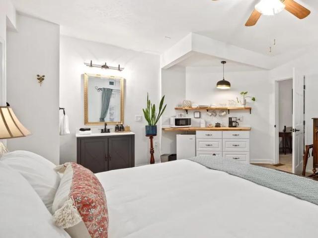 Bedroom of Flora House Denver, with white walls and linen, small kitchenette and vintage luxury furnishings