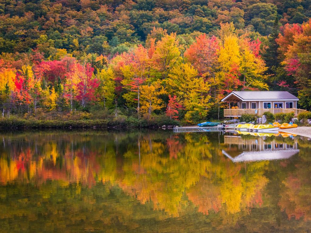 Boathouse surrounded by autumn trees, reflecting in Echo Lake, in Franconia Notch State Park, New Hampshire