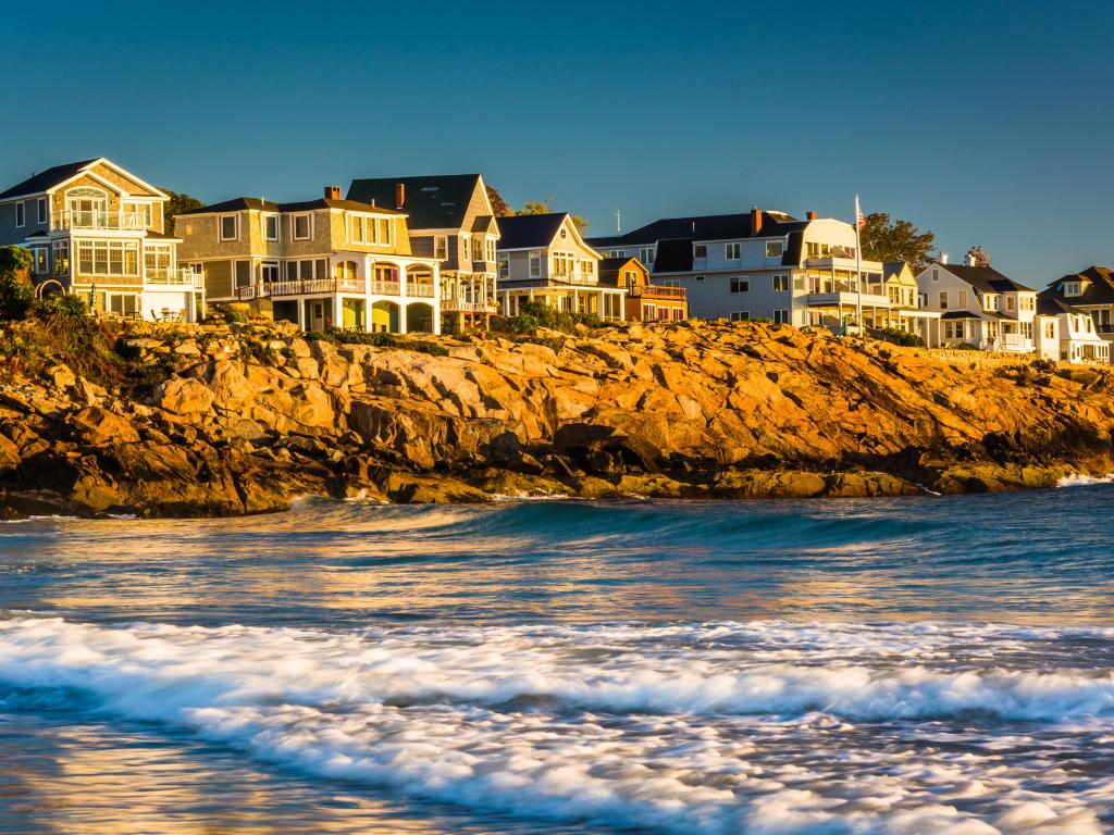 Waves in the Atlantic Ocean and houses on cliffs in York, Maine.