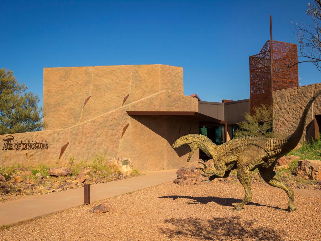 Red facade of the museum and the raptor statue outside on a sunny day