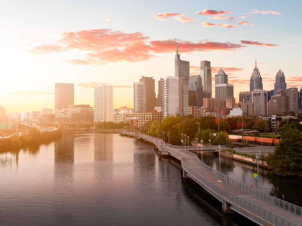 Philadelphia, Pennsylvania, USA with an aerial panoramic view of the downtown city taken during sunset with the river in the foreground.