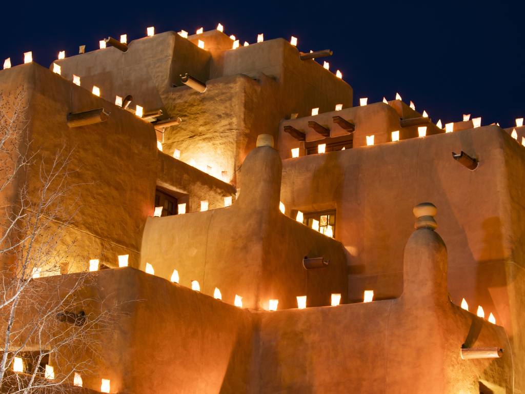 Candles are lit up on ledges around a traditional southern style building after dark