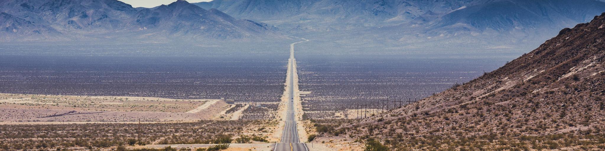 Route 66, USA with a classic panorama view of an endless straight road running through the barren scenery of the American Southwest with extreme heat haze on a beautiful hot sunny day with blue sky in summer