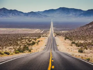 Route 66, USA with a classic panorama view of an endless straight road running through the barren scenery of the American Southwest with extreme heat haze on a beautiful hot sunny day with blue sky in summer