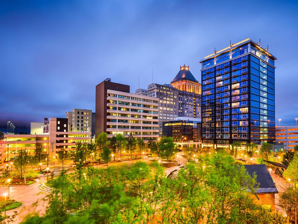 Greensboro, North Carolina, USA with the downtown city skyline taken at night, trees in the foreground. 