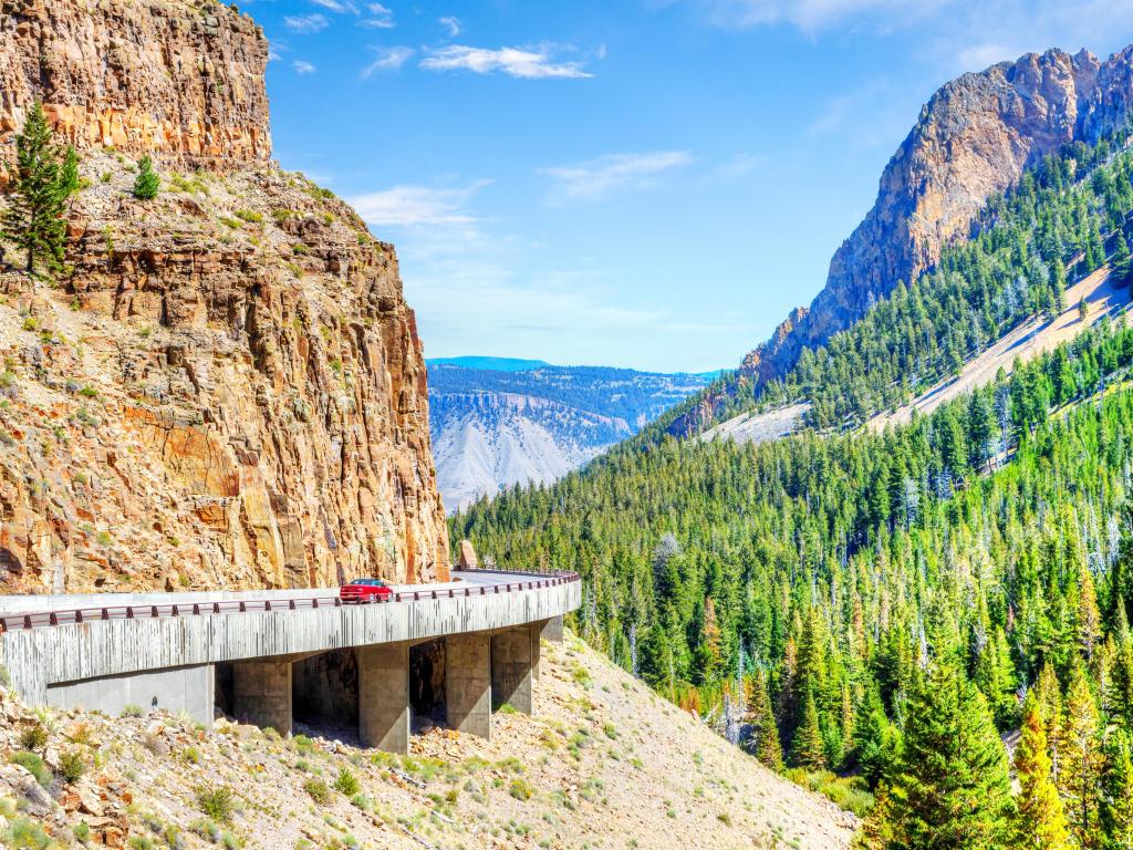 Red car on Grand Loop Road through Golden Gate Canyon at Kingman Pass in the northwestern region of Yellowstone National Park, Wyoming, USA.