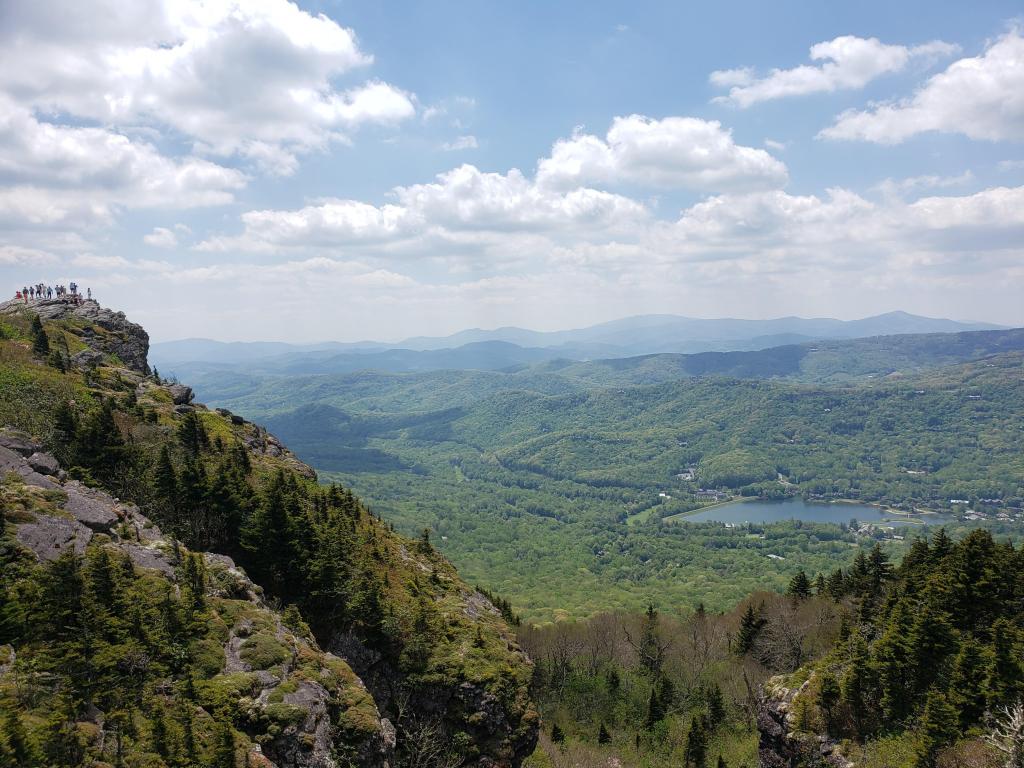 View from the top of a hill onto forests and a lake on a partially cloudy day