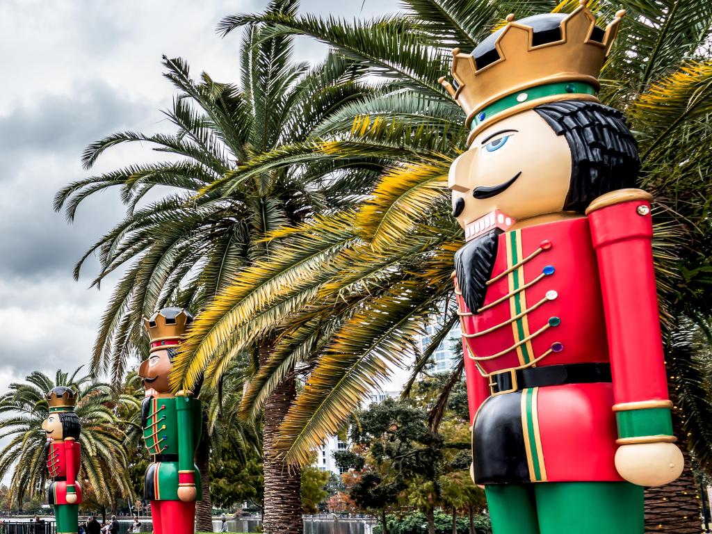 A giant Nutcracker Christmas decoration stands in front of a row of palm trees at Eola Park, Downtown Orlando, Florida