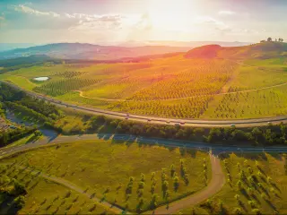 Aerial panorama of green fields and gently rolling hills - Tuggeranong Parkway and National Arboretum at sunset in Canberra, Australia