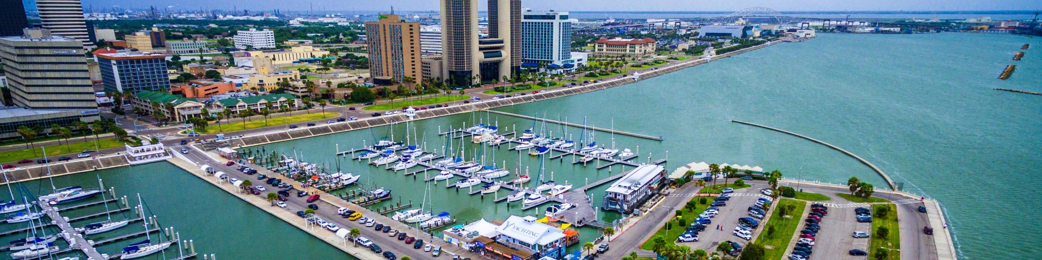 Skyline view of Corpus Christi Texas, overlooking harbor bridge and rows of piers filled with boats and sailboats 