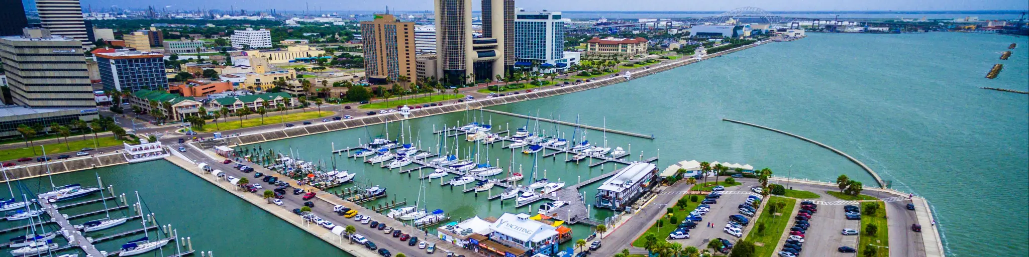 Skyline view of Corpus Christi Texas, overlooking harbor bridge and rows of piers filled with boats and sailboats 