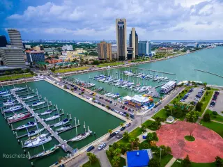 Skyline view of Corpus Christi Texas, overlooking harbor bridge and rows of piers filled with boats and sailboats 