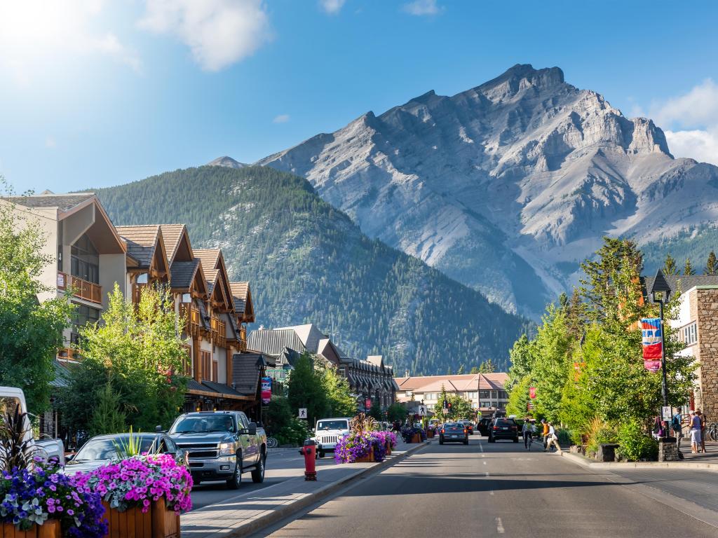 Banff, Alberta, Canada with a scenic street view of the Banff Avenue on a sunny summer day and the mountains in the distance.