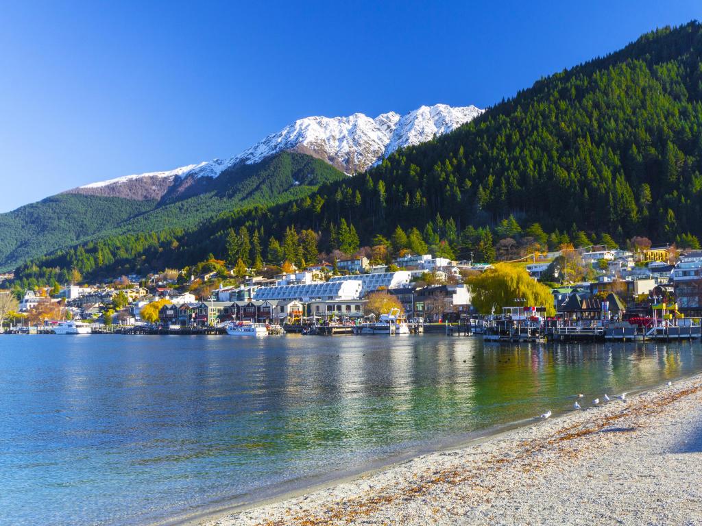 Queenstown, New Zealand with a beautiful landscape of Lake Wakatipu and buildings in front of mountains.
