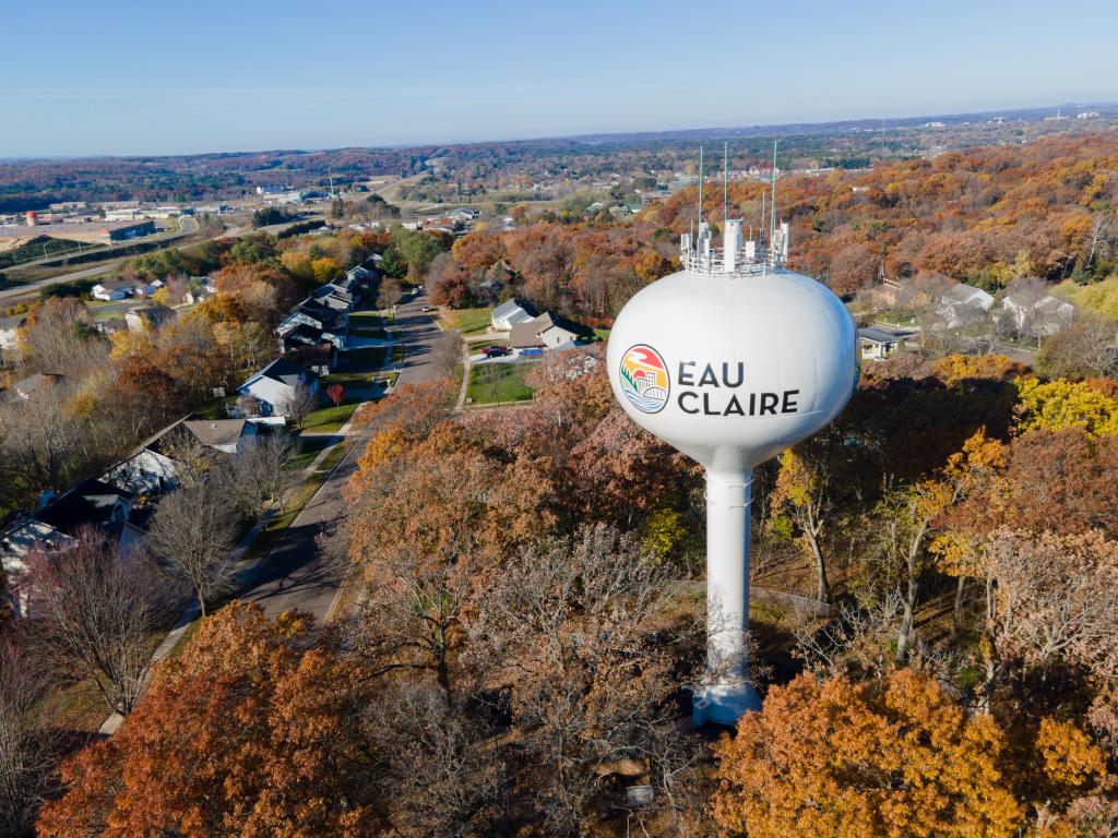 Aerial view of the tall, white water tower at Eau Claire, Wisconsin, with colorful fall foliage all around