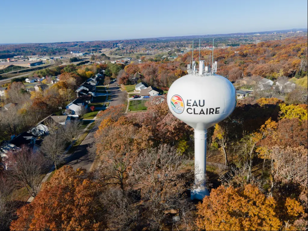Aerial view of the tall, white water tower at Eau Claire, Wisconsin, with colorful fall foliage all around