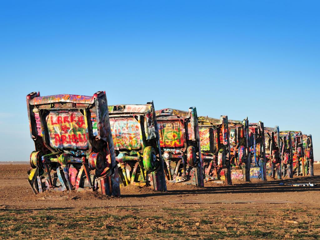Graffiti-covered cars stand upright in the desert