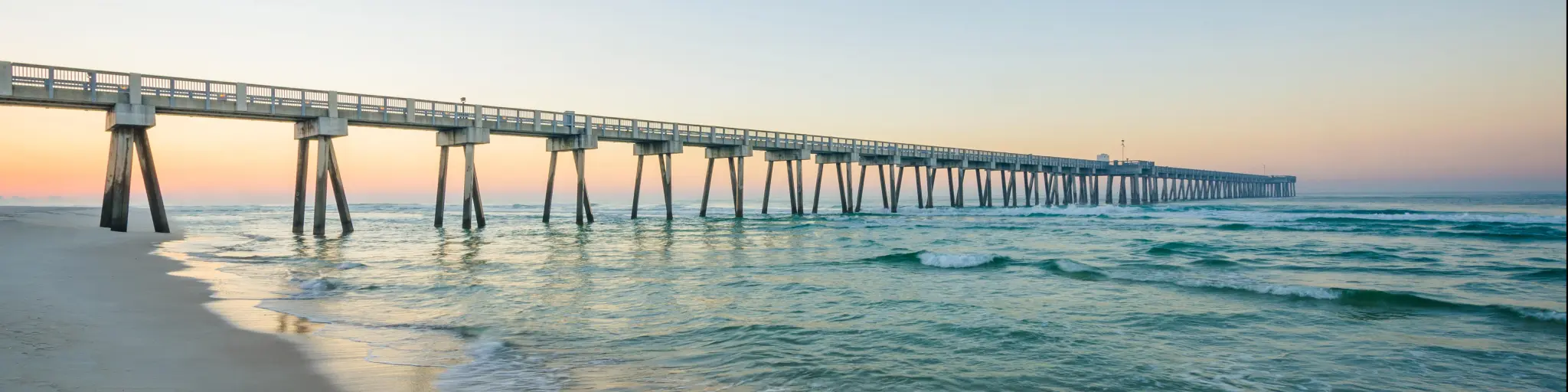 M.B. Miller County Pier and Gulf of Mexico at sunrise, in Panama City Beach, Florida, with white sands below