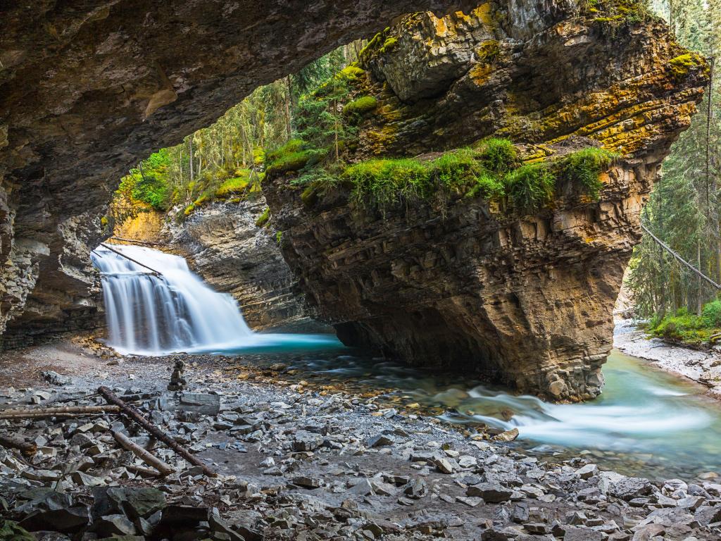 Johnston Canyon, Lower Falls, Banff, Canada taken at Waterfall Cave with large rocks surrounding the water.