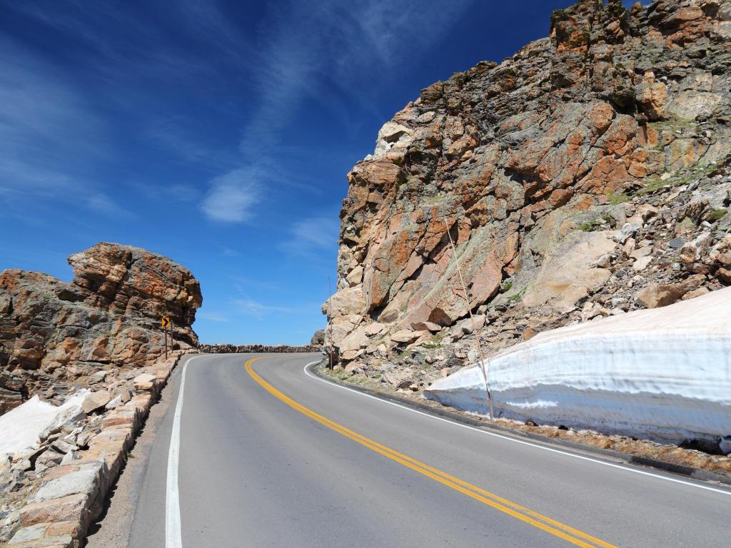 Winding Trail Ridge Road through Rocky Mountain National Park, surrounded with steep rockfaces and blue skies